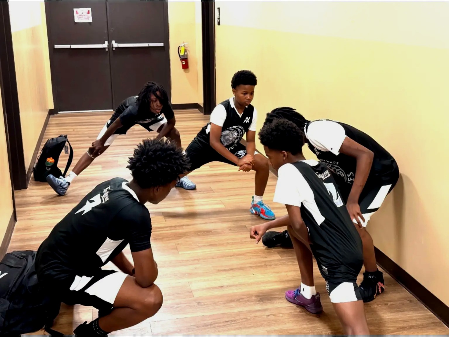 N.O.W. Wolves players in black and white uniforms stretching together before a game