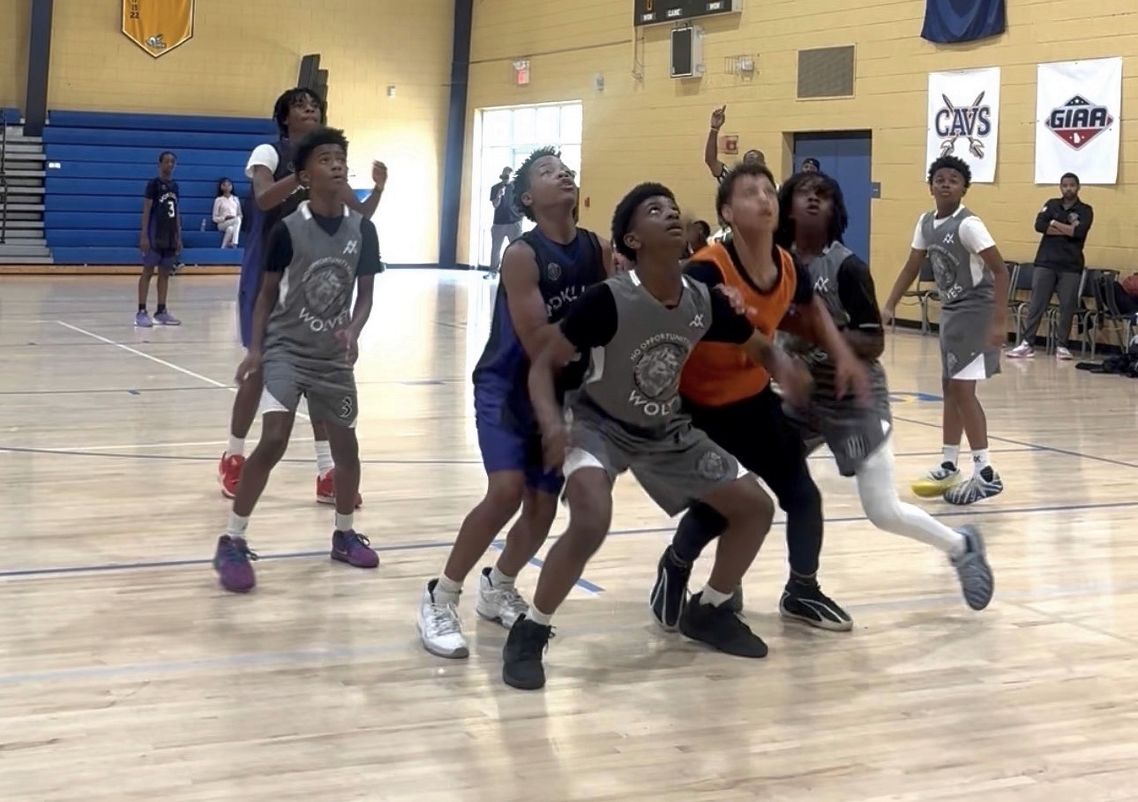 Wolves players in gray jerseys positioning themselves for a rebound during a basketball game