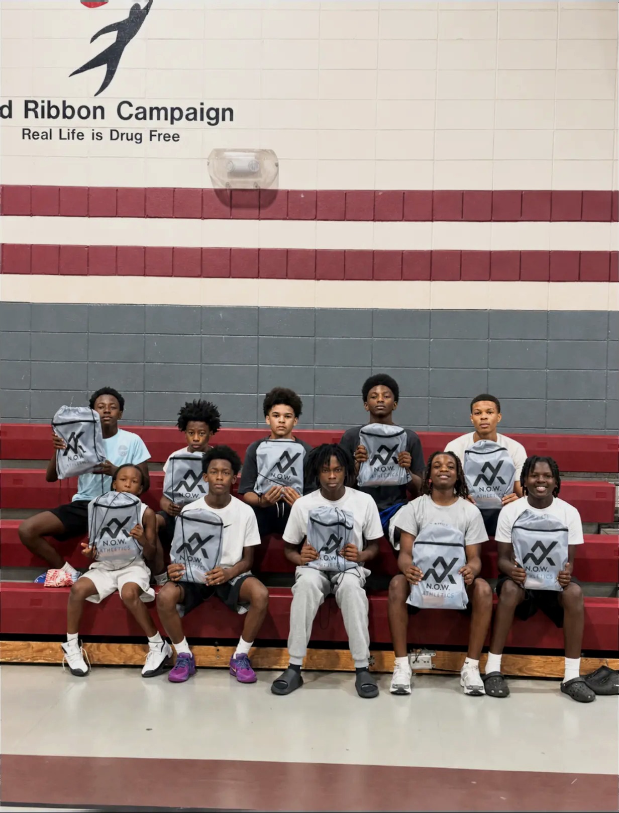 N.O.W. Wolves players seated on red bleachers, holding up their team jerseys