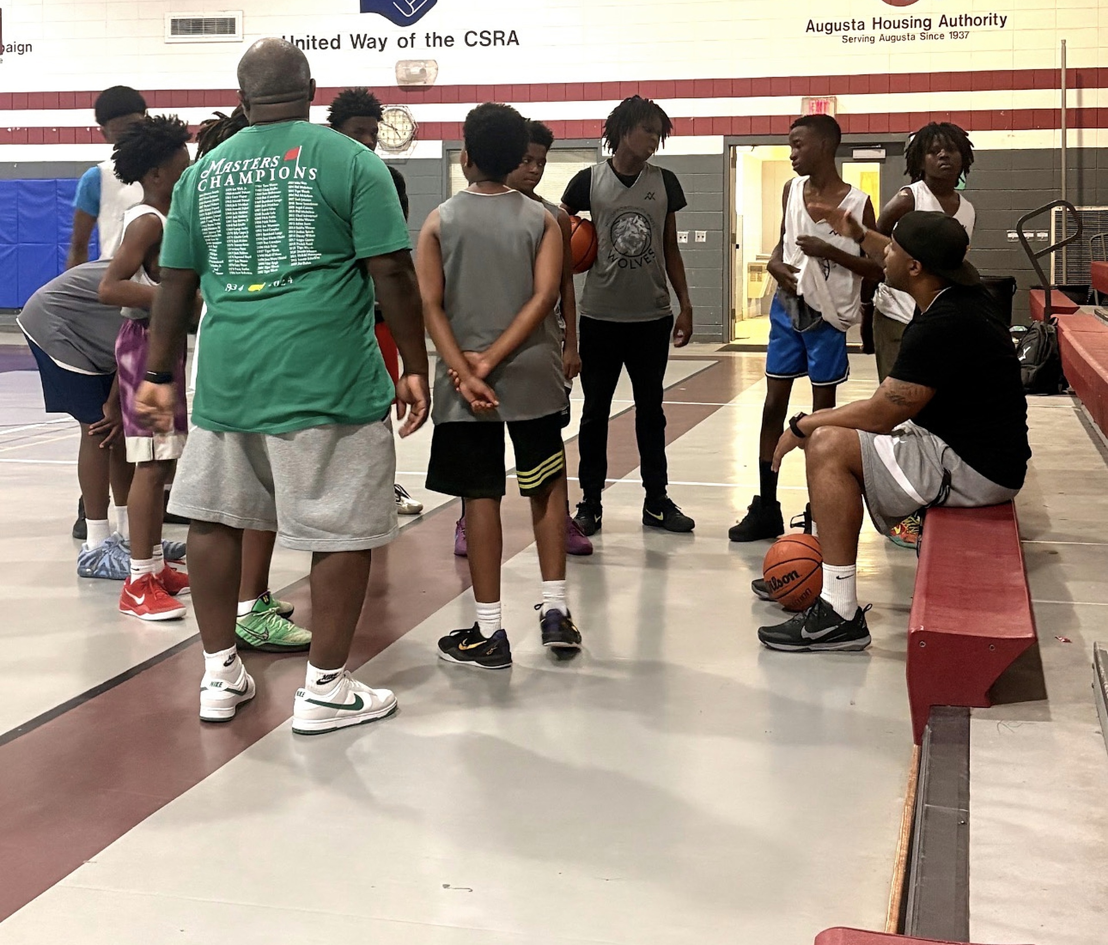 Players and coaches gathered beside the gym bleachers during practice